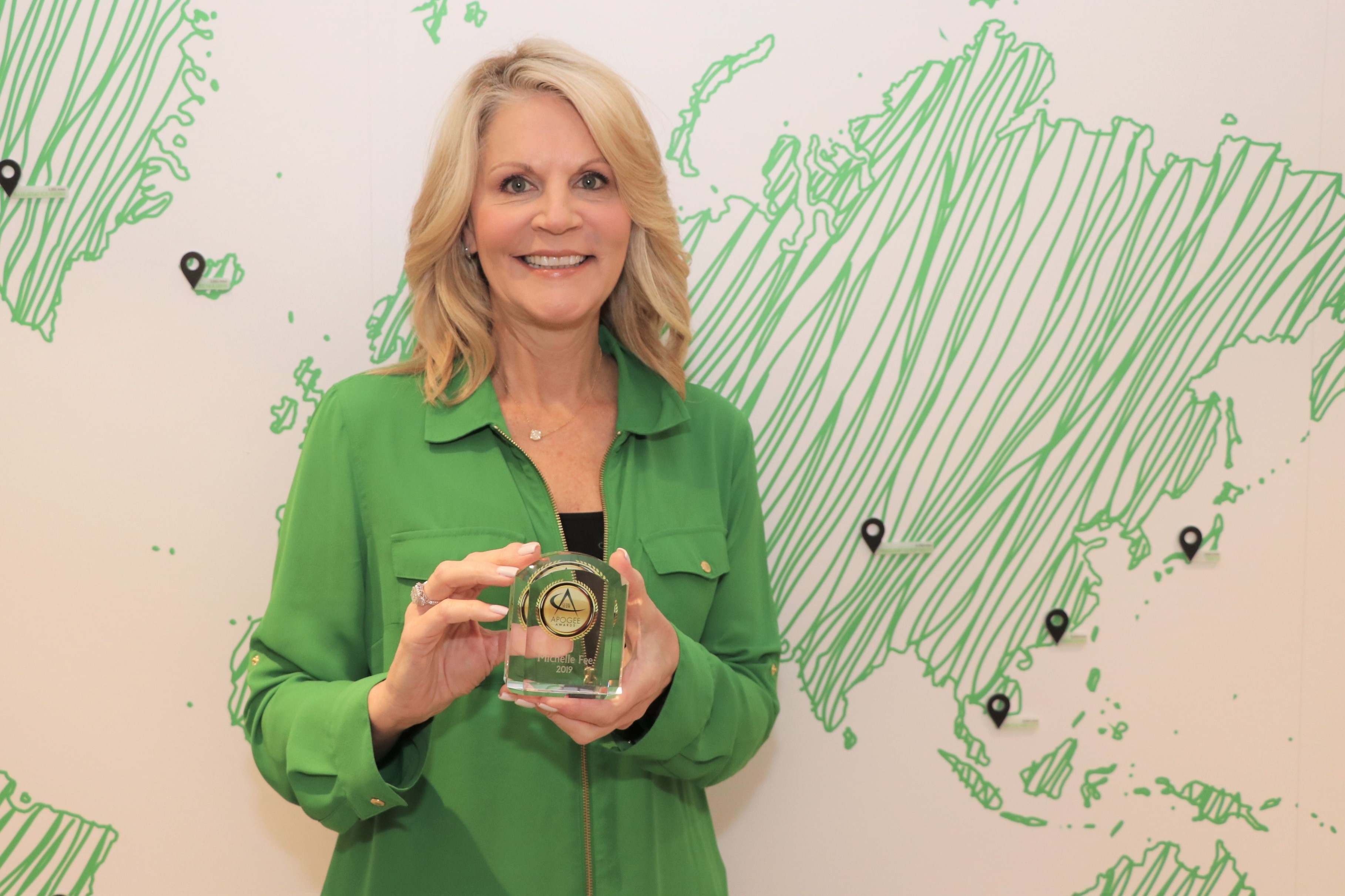Michelle Fee, CEO and founder of Cruise Planners, proudly shows off her Apogee Award as a Distinguished CEO by South Florida Business & Wealth